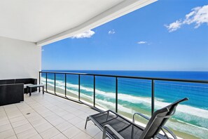 Uma varanda com vista para o oceano, uma área de estar com mesa e um corrimão.