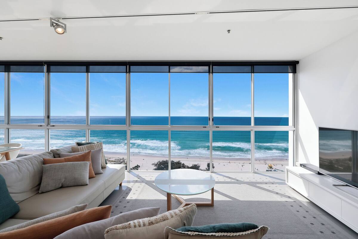 A modern living room with a large window overlooking a beach.