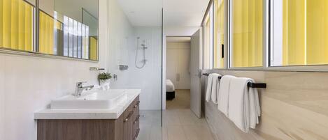 A modern bathroom with a glass shower enclosure, a wooden vanity, and a large mirror.