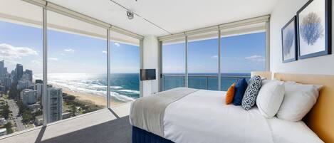 Une chambre d’hôtel située dans un immeuble de grande hauteur, dotée d’un grand lit, d’une vue sur la ville et d’un balcon.