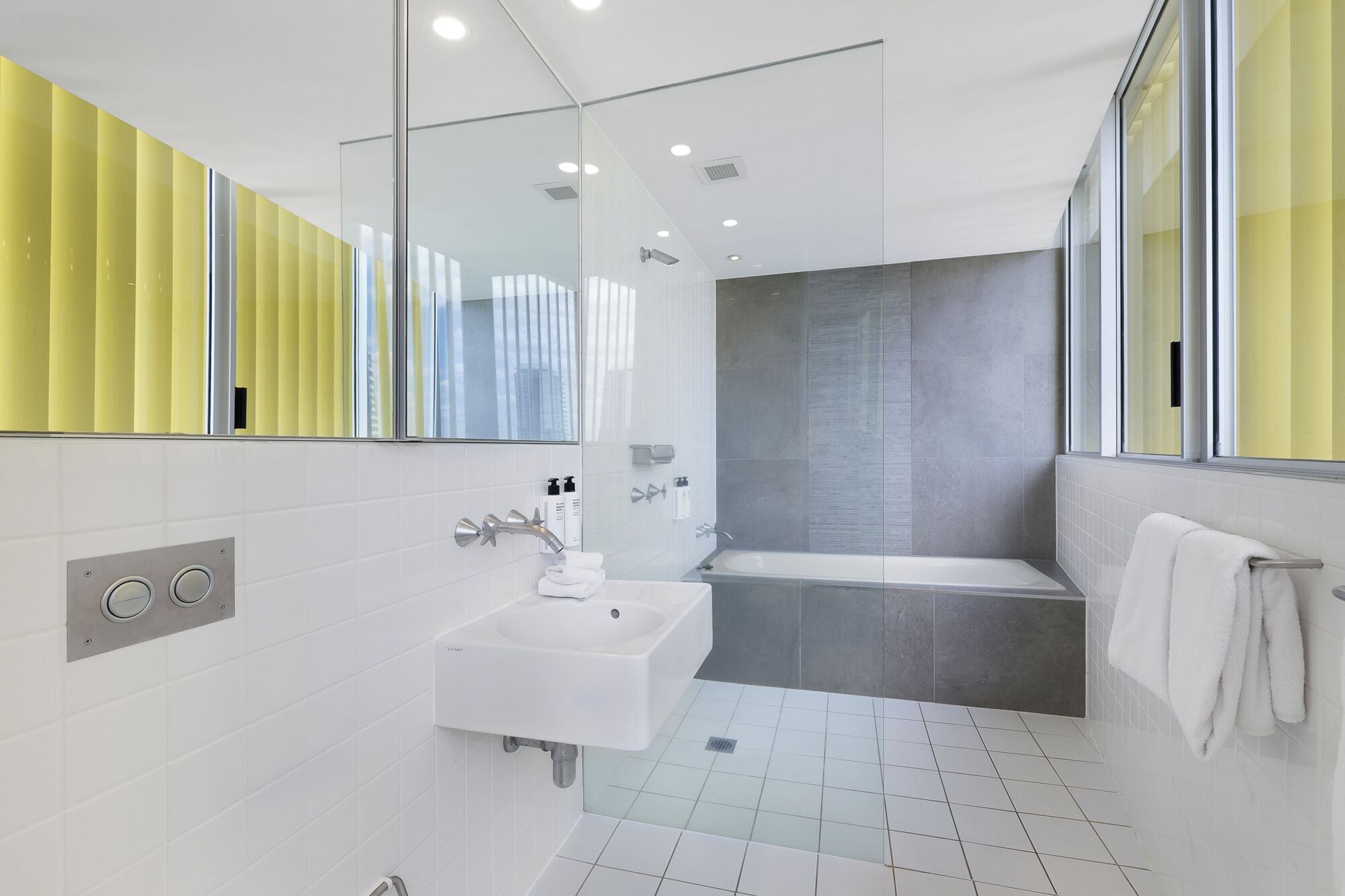 Een moderne badkamer met een witte wastafel, een douchecabine van glas en een bad.