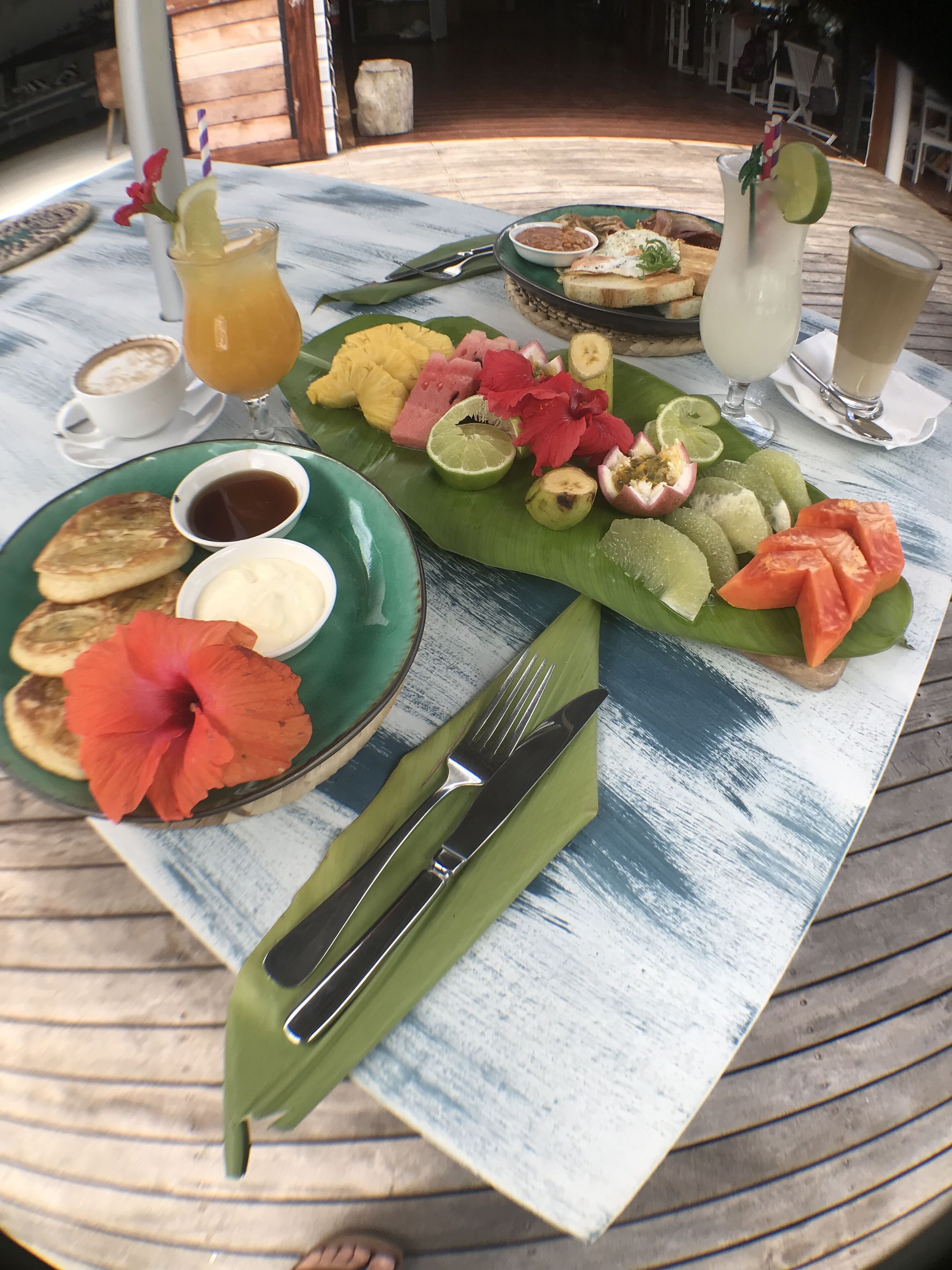 Una mesa de desayuno con diversos alimentos, como panqueques, frutas y bebidas.