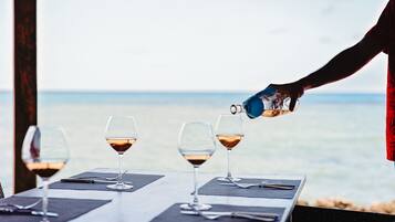 Una mesa con cuatro copas de vino y una persona sirviendo vino en una de ellas.