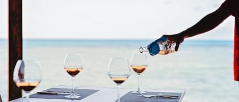 A table with four wine glasses and a person pouring wine into one of them.