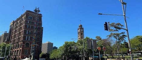 A city intersection with a historic building, a clock tower, and traffic lights.