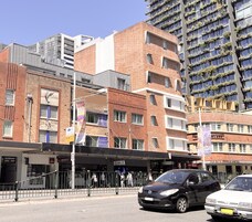 Um edifício de vários andares com uma combinação de arquitetura em tijolo e moderna, apresentando diversas lojas e placas.