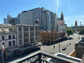 Paisagem urbana com mistura de edifícios modernos e históricos, incluindo uma torre do relógio imponente ao fundo.