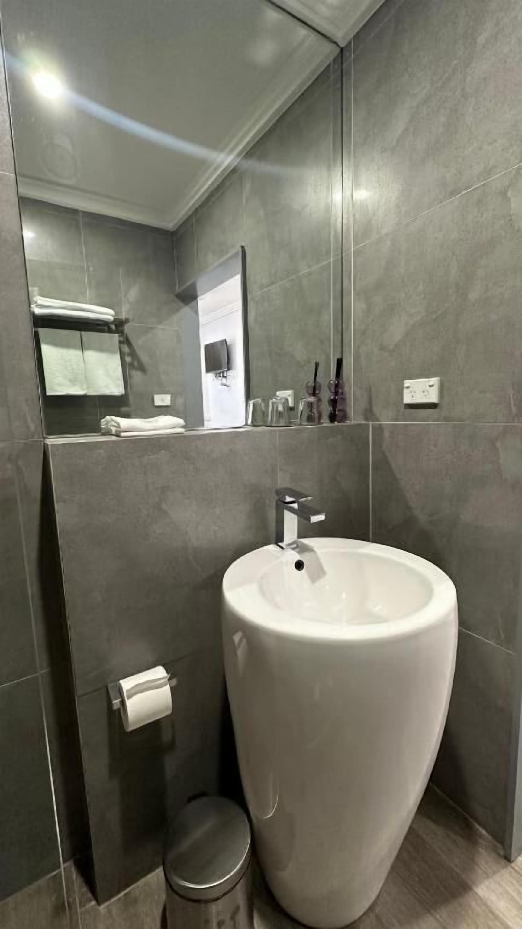 A modern bathroom with a large white sink, a mirror, and a toilet.