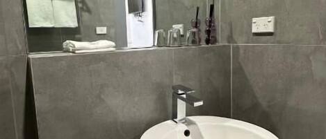 A modern bathroom with a large white sink, a mirror, and a toilet.