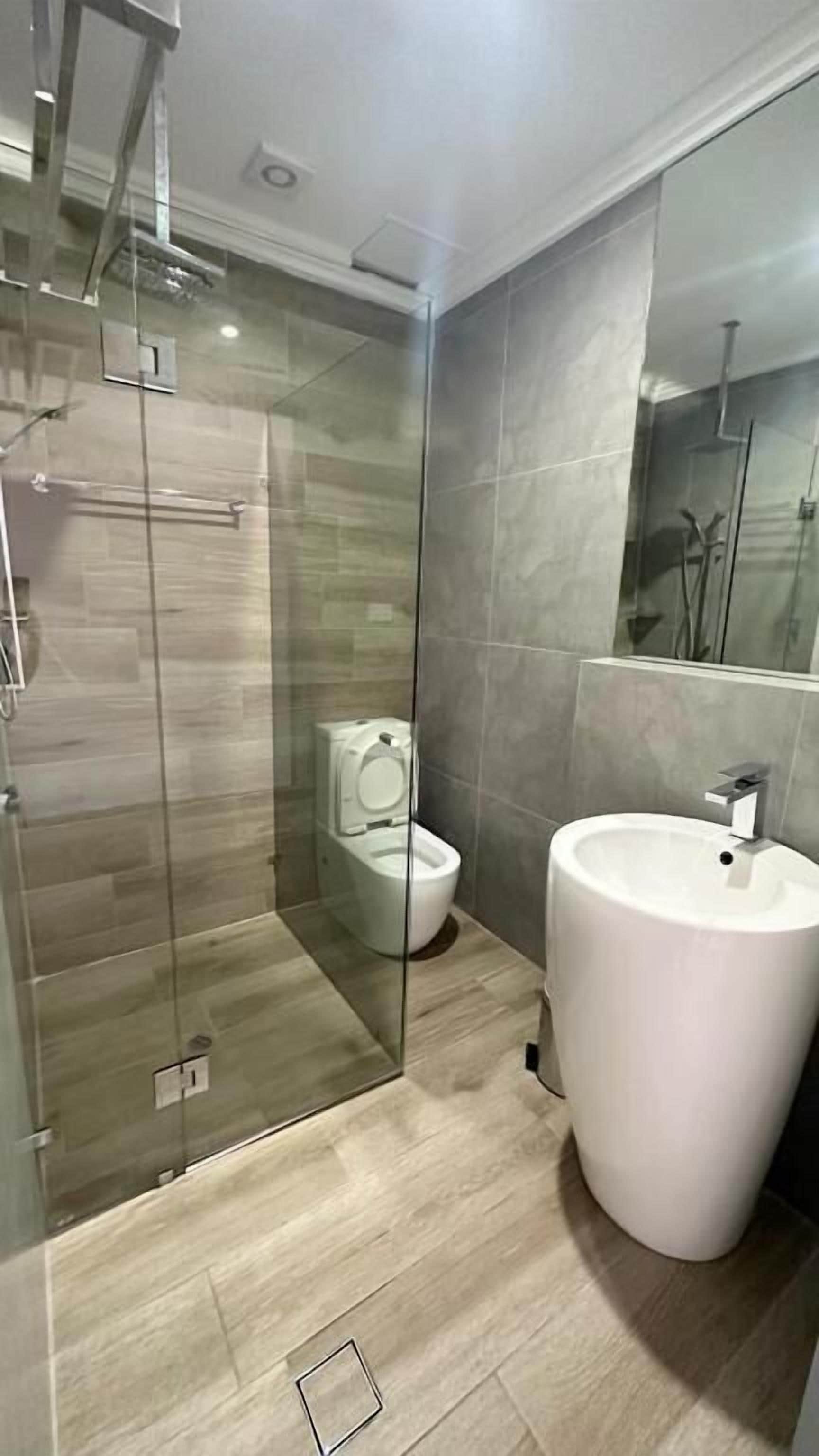 Une salle de bain moderne avec une douche à parois de verre, des toilettes et un grand lavabo.