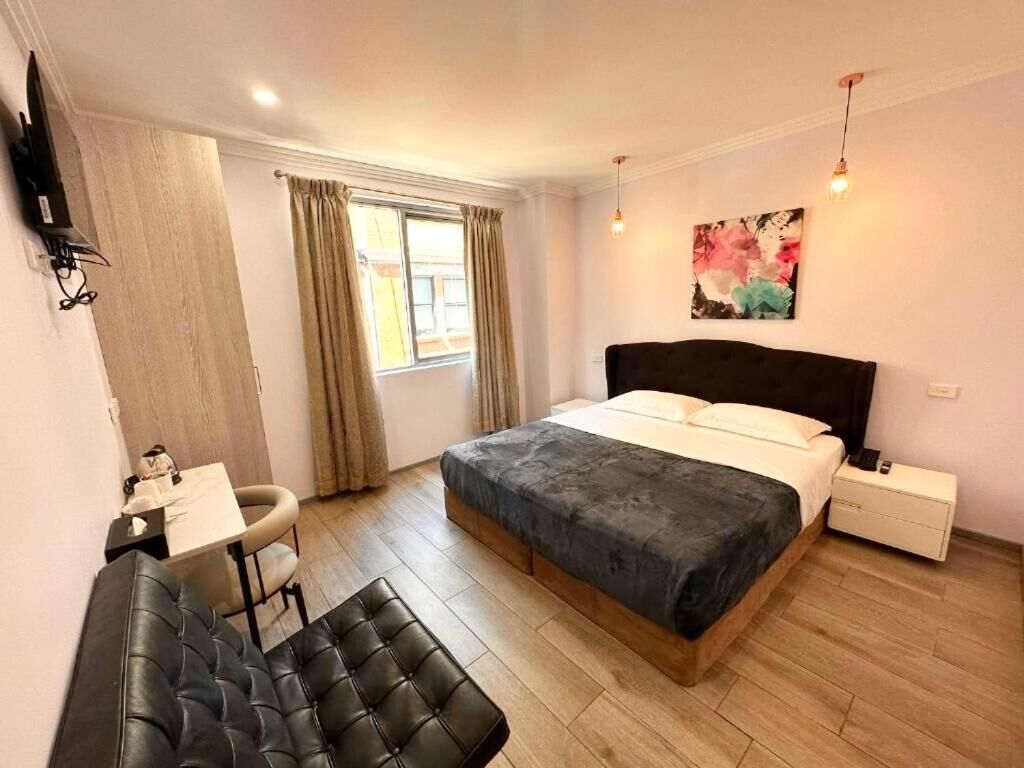 Ein Schlafzimmer mit Bett, Nachttisch, Lampe und einem Fenster mit Vorhängen.