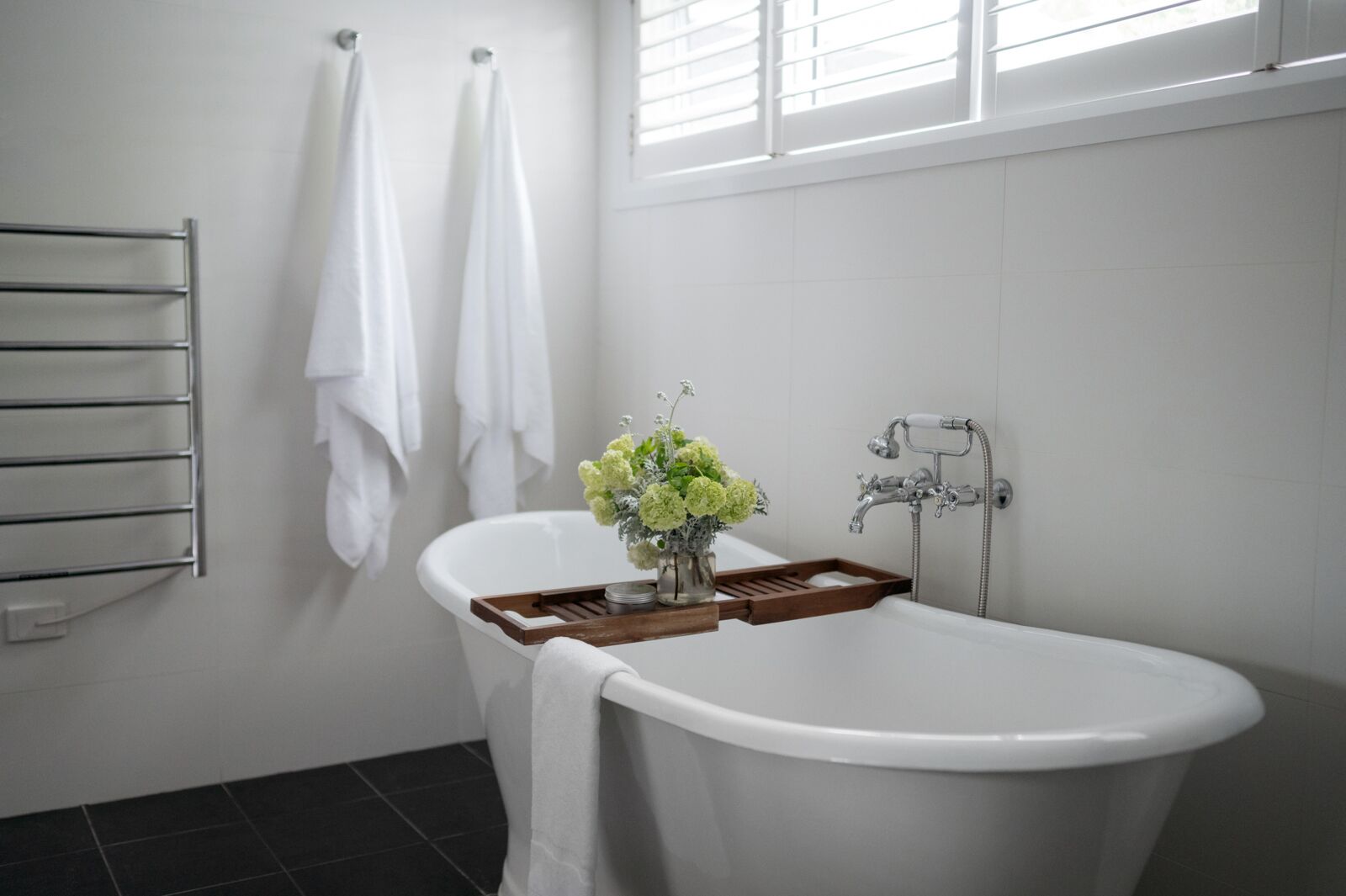 Une salle de bain avec une baignoire sur pieds, un porte-serviettes et une fenêtre avec des stores.