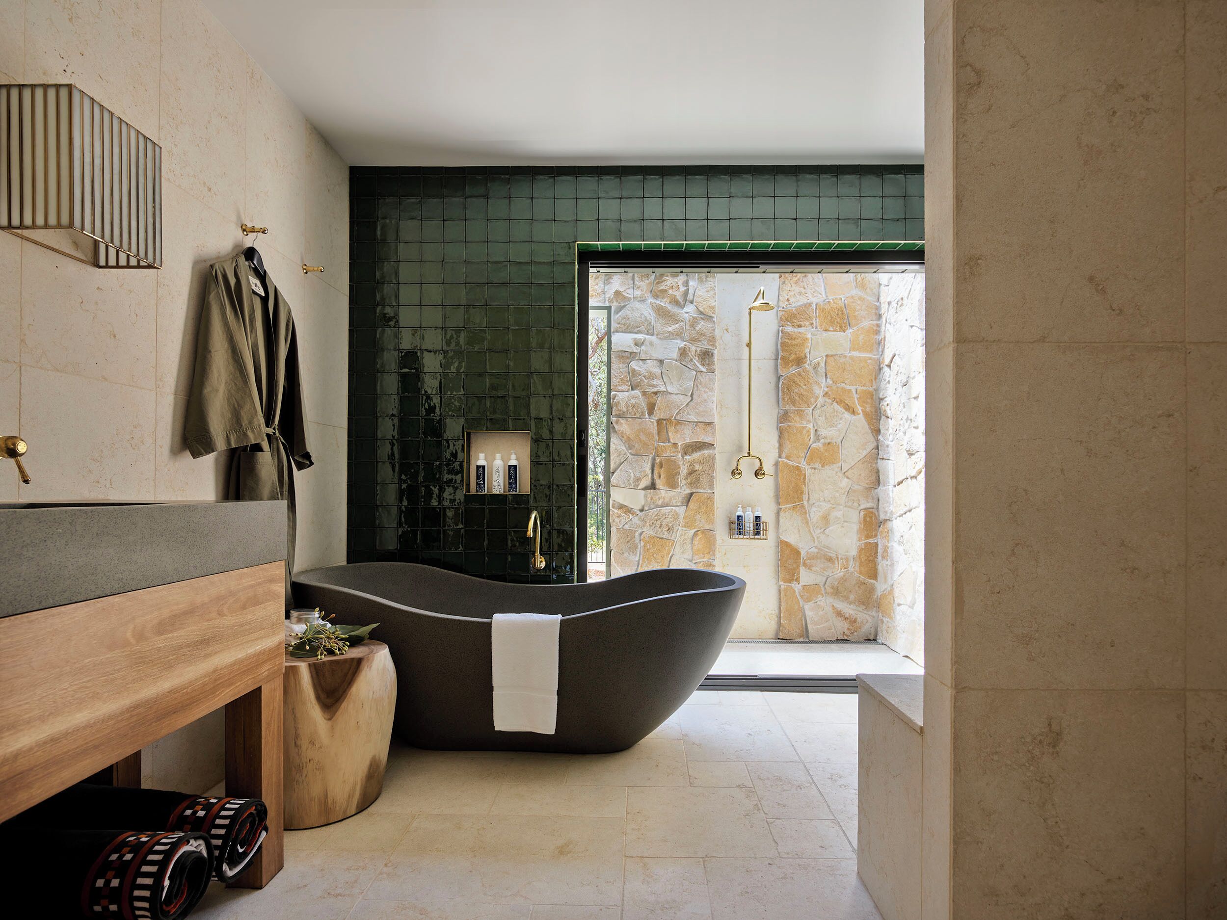A modern bathroom with a freestanding bathtub, a wooden vanity, and a stone shower enclosure.