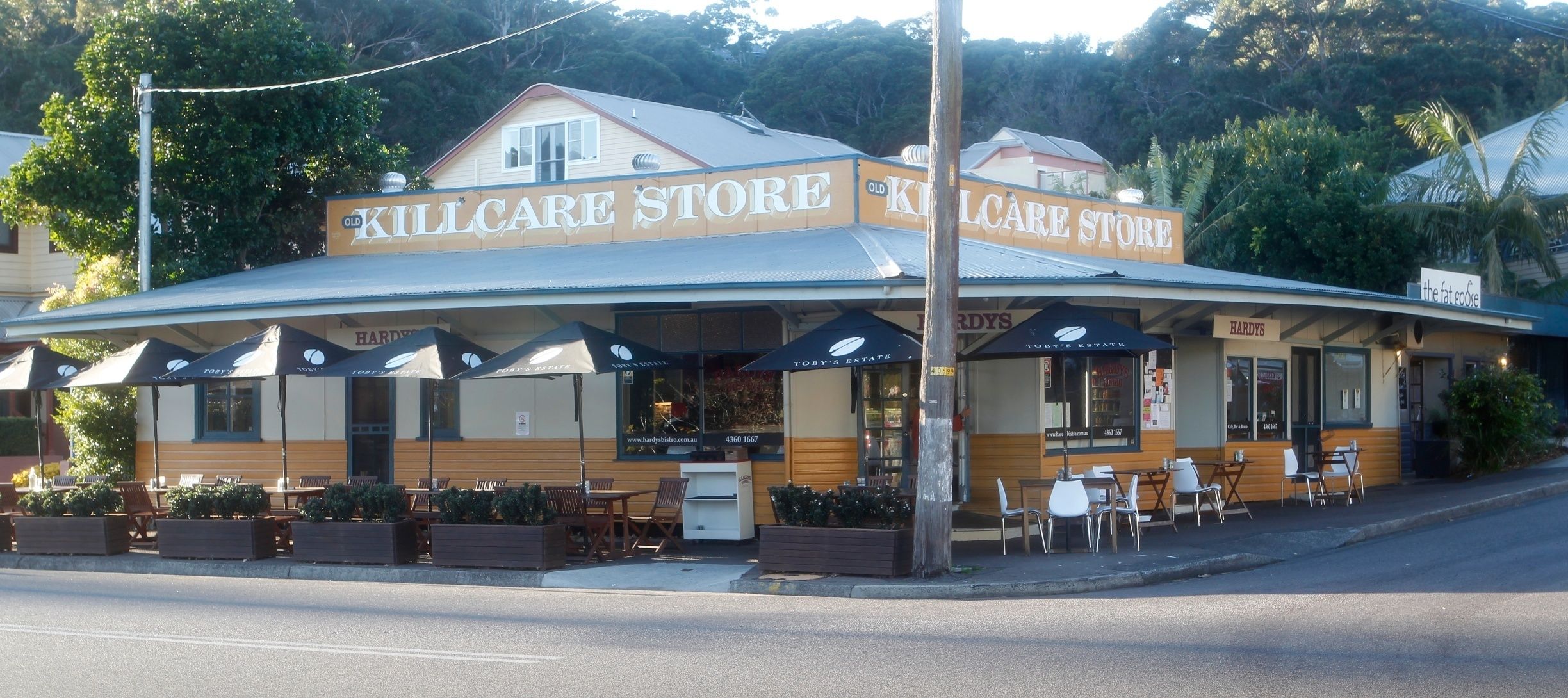 A building with a sign reading "KILLCARE STORE" and "TORY'S ESTATE". There are outdoor tables and chairs, and a sidewalk in front.