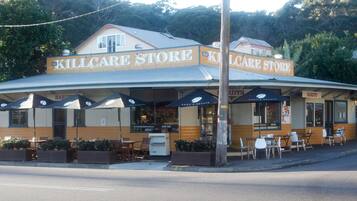A building with a sign reading "KILLCARE STORE" and "TORY'S ESTATE". There are outdoor tables and chairs, and a sidewalk in front.