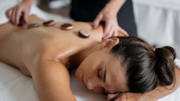 A person receiving a back massage with stones.