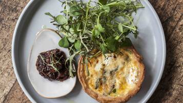 Une assiette avec une quiche, un petit bol de chutney et une portion de légumes verts.