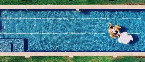 An aerial view of a swimming pool with lounge chairs and umbrellas.