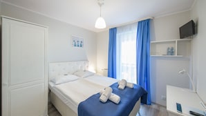 Habitación de hotel con cama, escritorio, televisión y ventana con cortinas.