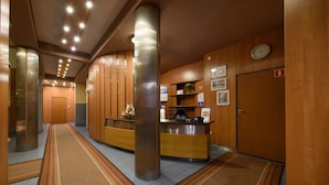 Una zona de recepción con un mostrador de madera, un reloj en la pared y una mesa de recepción.