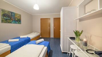 Una habitación de hotel con dos camas individuales, un escritorio con silla, un armario y un cuadro en la pared.
