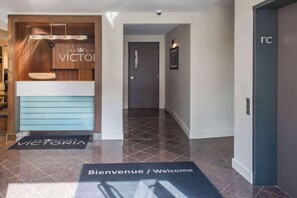 A hotel reception area with a modern design, a reception desk, and a door labeled "rc". - Les Suites Victoria, an Ascend Collection Hotel (Gatineau)