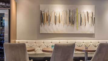 A modern lounge area with a tufted sofa, round tables, and a large abstract painting on the wall.