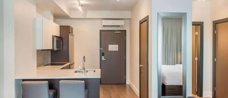 Habitación de hotel compacta con kitchenette, un pequeño rincón de descanso y una cama con vistas.