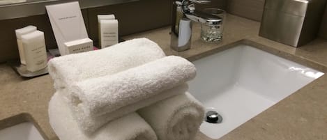 A bathroom with a sink, a mirror, and toiletries including towels and a tissue box.