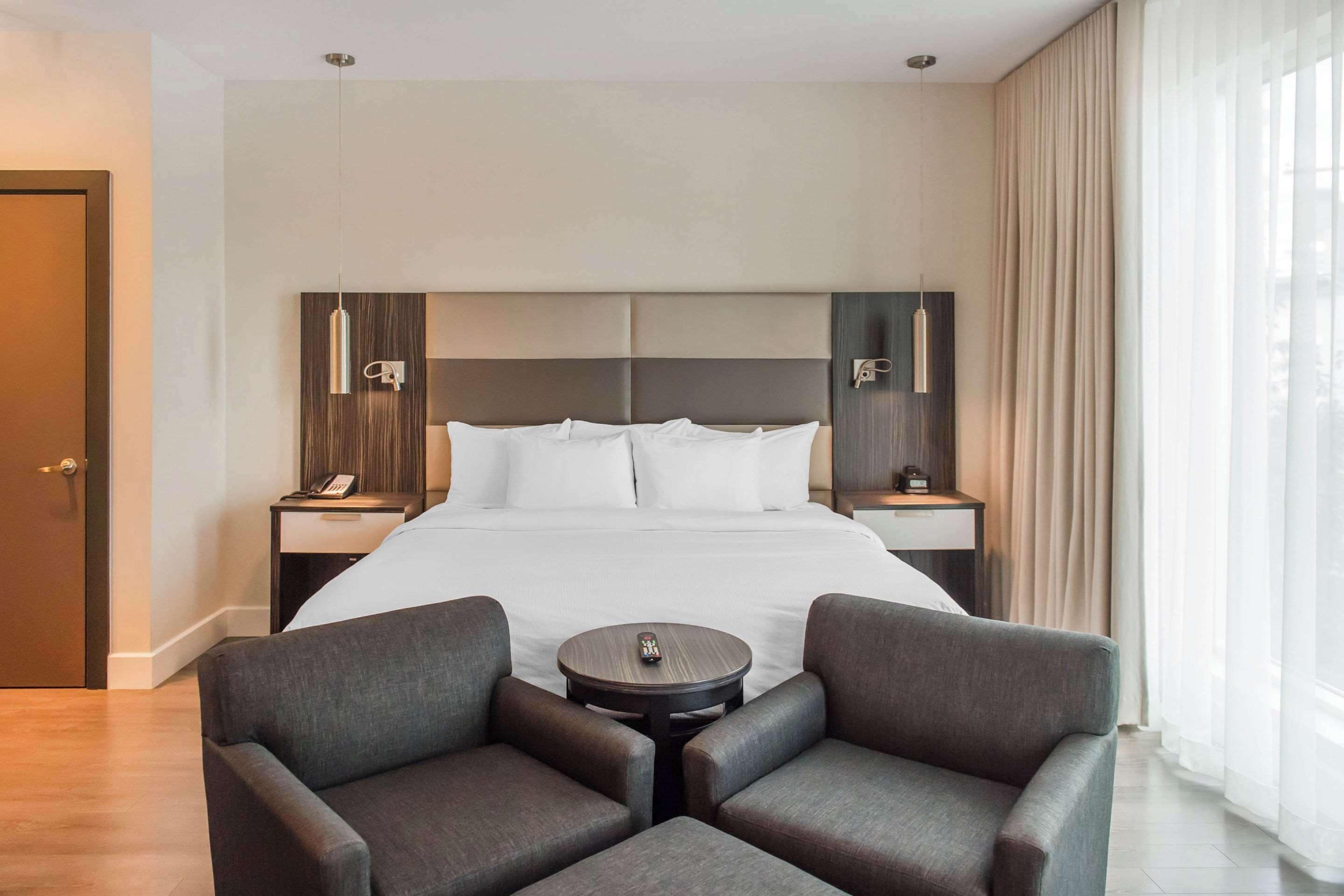 A hotel room with a large bed, two bedside tables, a small round table, and two armchairs.
