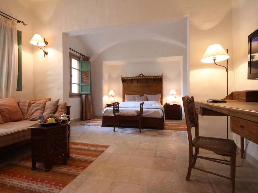 A bedroom with a bed, a desk, a chair, a sofa, and a TV.