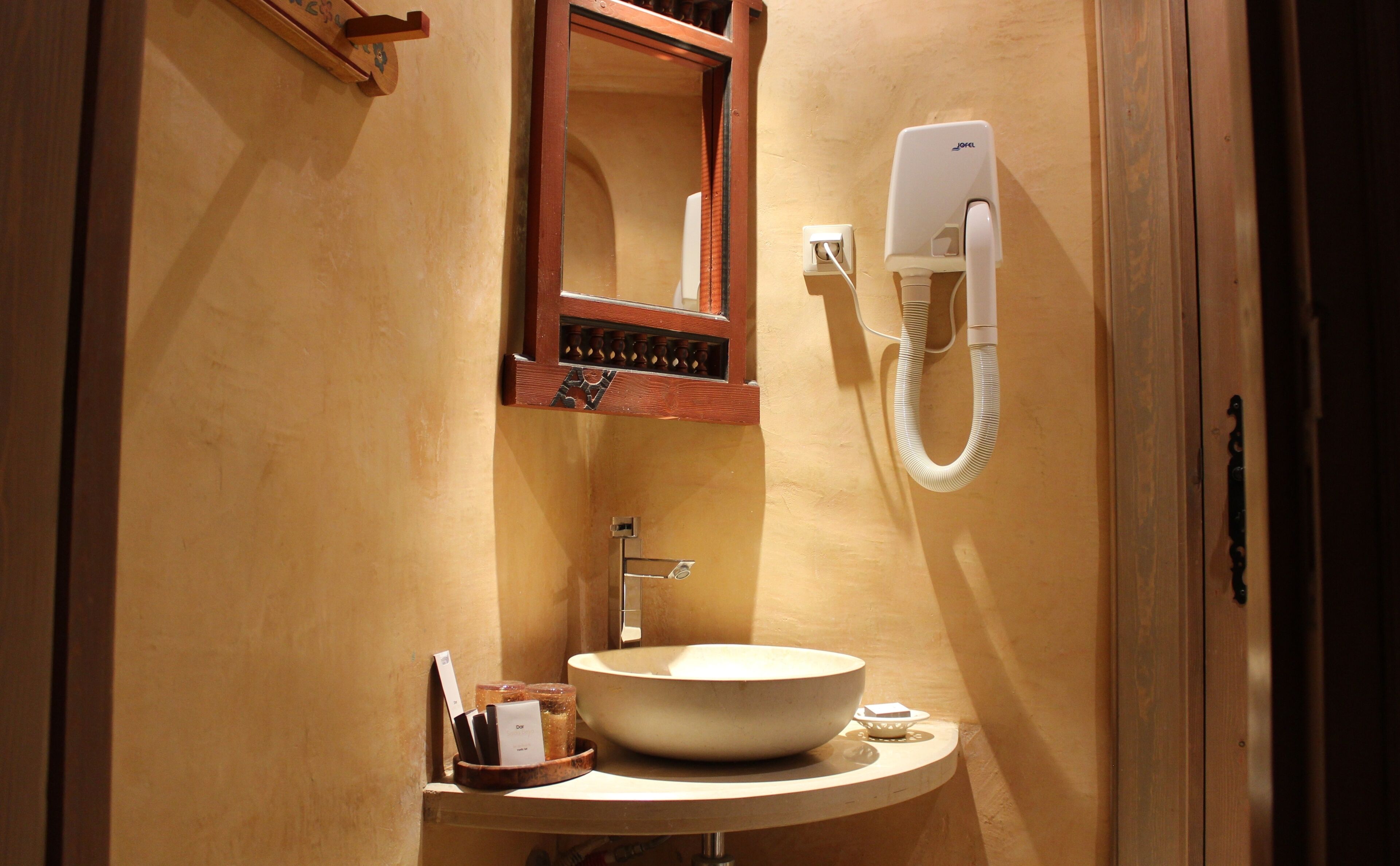 A bathroom with a wooden vanity, a sink, a mirror, and a wall-mounted telephone.