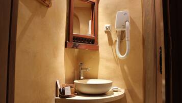 A bathroom with a wooden vanity, a sink, a mirror, and a wall-mounted telephone.