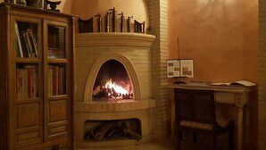 Une cheminée avec un manteau de cheminée, une bibliothèque et une table avec une lampe et des papiers.