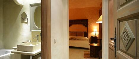 Une chambre d’hôtel avec une salle de bain, un lit, une table de chevet et une lampe.