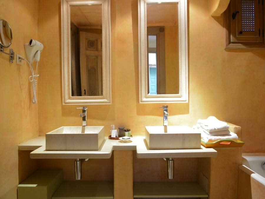 Baño con dos lavamanos, espejos y un perchero para toallas.