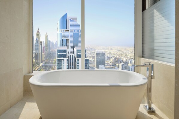 Ein modernes Badezimmer mit freistehender Badewanne, einem großen Fenster und Blick auf eine Stadtlandschaft.