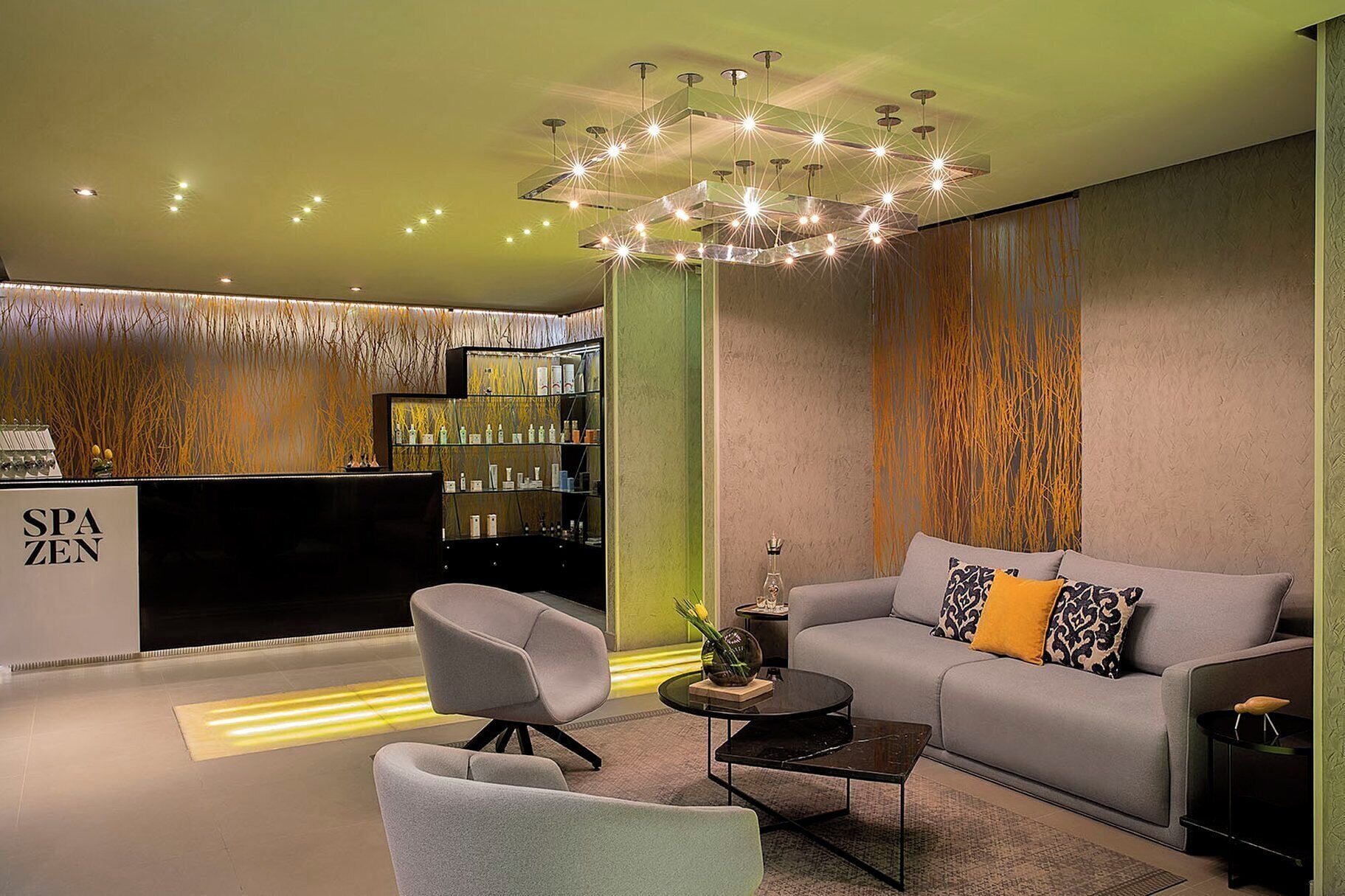 A modern interior with a sofa, chairs, a coffee table, a decorative light fixture, and a reception desk.