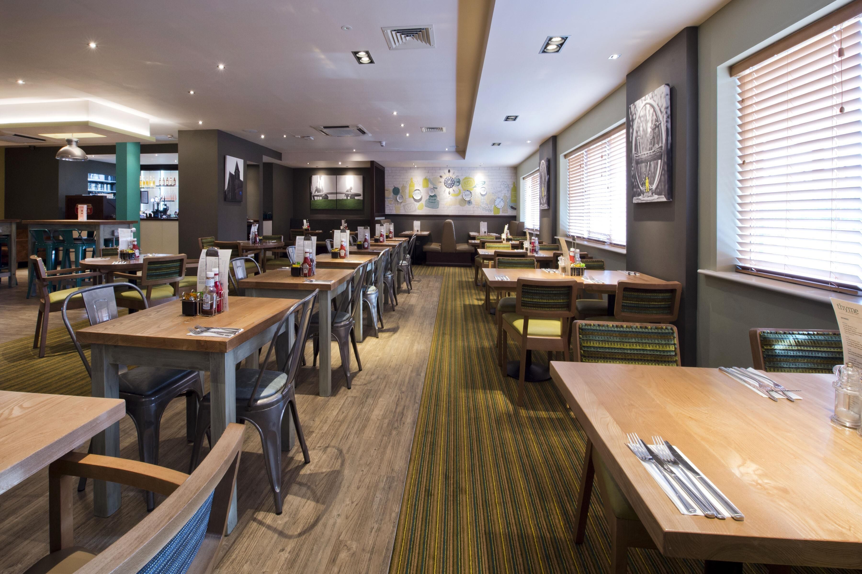 A restaurant with multiple tables and chairs, a counter area, and artwork on the walls.