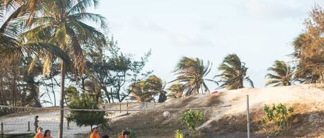 Una cancha de voleibol de playa arenosa con jugadores con ropa informal.