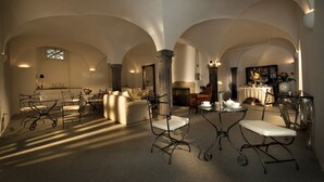A spacious room with high ceilings and arched structures, featuring a fireplace, seating area, and a dining table. - Antiq Palace (Ljubljana)