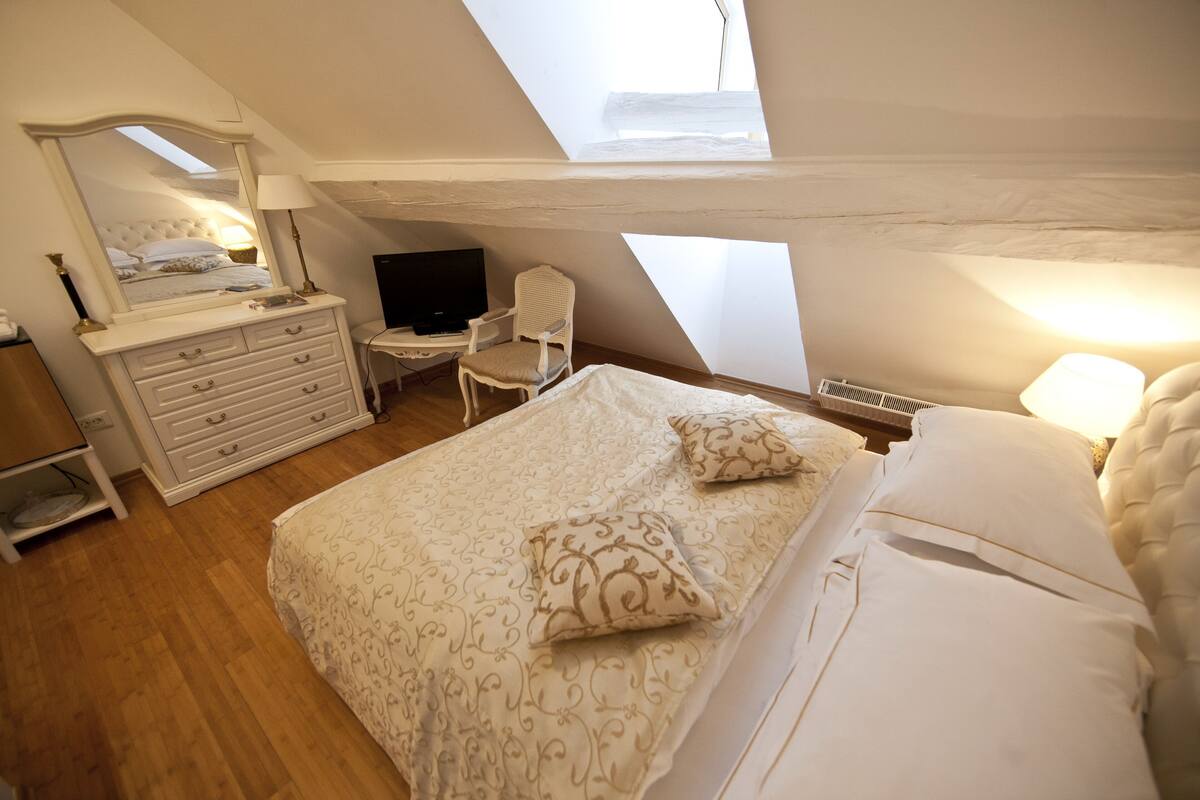 A bedroom with a bed, a dresser, a chair, a desk, and a television.
