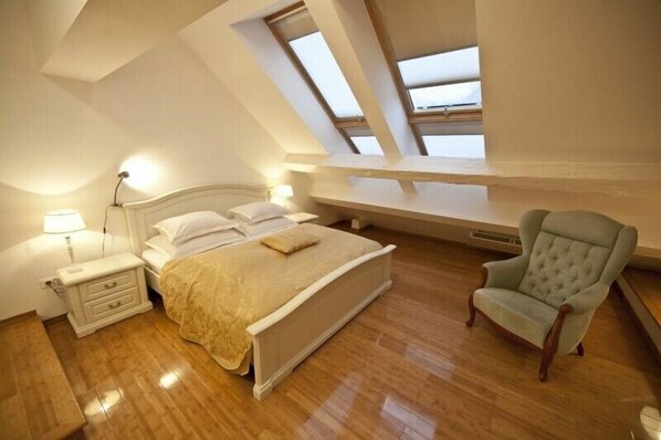 Un dormitorio con cama, mesita de noche, lámpara y una silla.