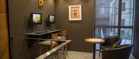 Un espacio de oficina moderno con un escritorio, sillas, una mesa redonda y dos monitores en la pared.