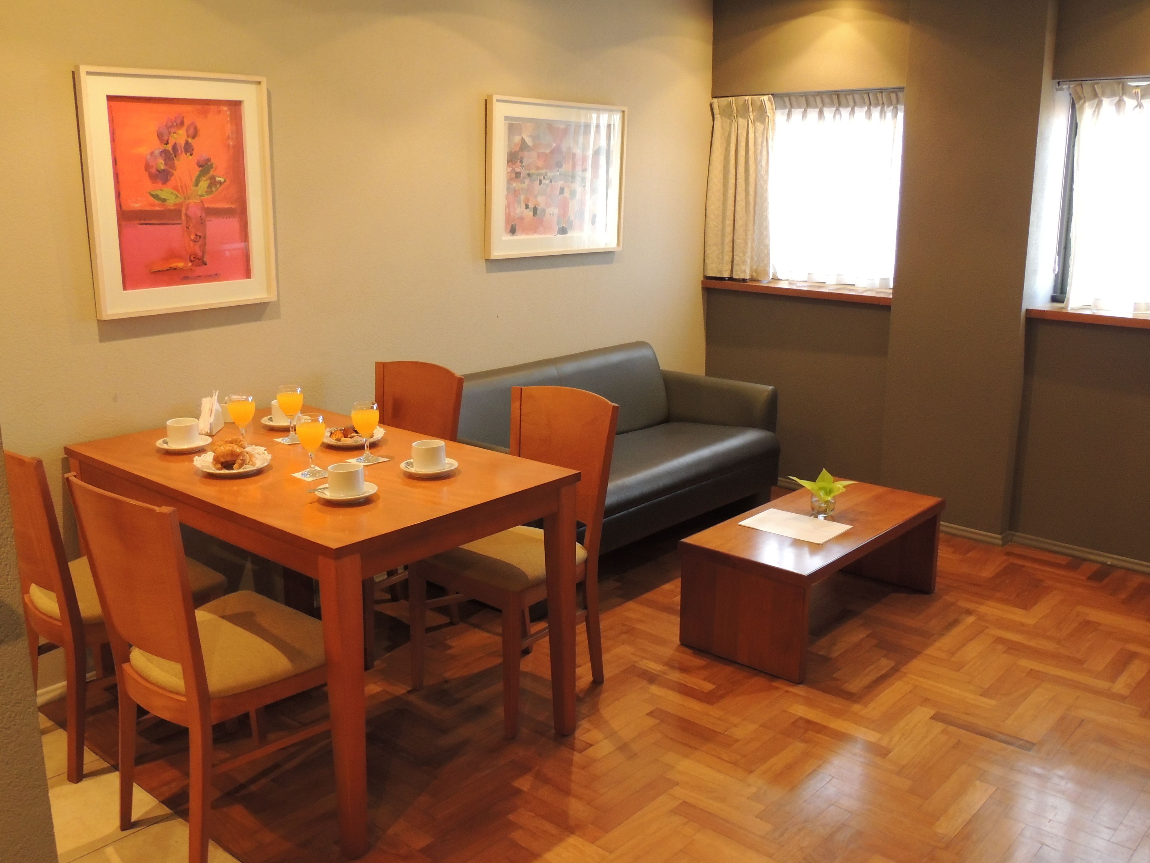 A dining area with a wooden table set for breakfast, a sofa, and a small coffee table.