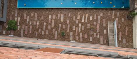 A rooftop pool with a blue water feature and a brick wall with a geometric pattern.