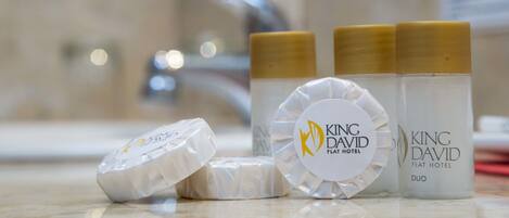 Tres velas del Hotel King David Flat Duo y un objeto con forma de diamante sobre una encimera de baño.