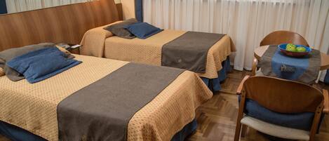A hotel room with two beds, a dining table, and a chair.