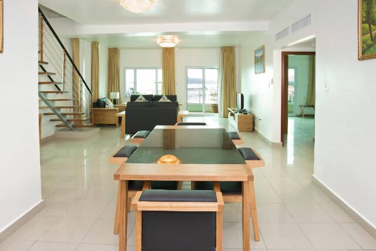 A spacious living area with a central table, a sofa, and a staircase.
