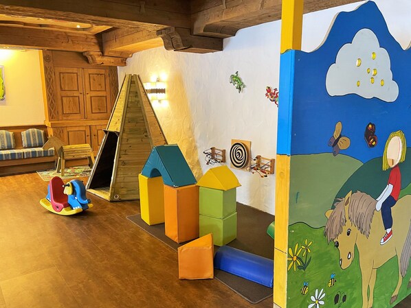 A play area with a slide, climbing structure, and colorful foam blocks. - Berghotel Tirol (Jungholz)